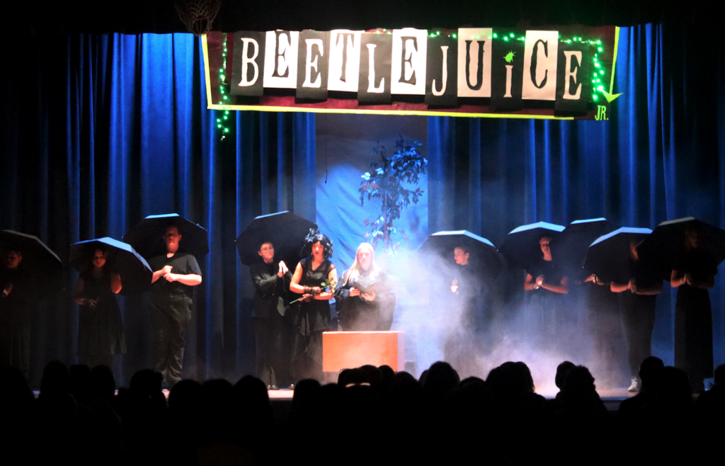 students standing on stage with umbrellas