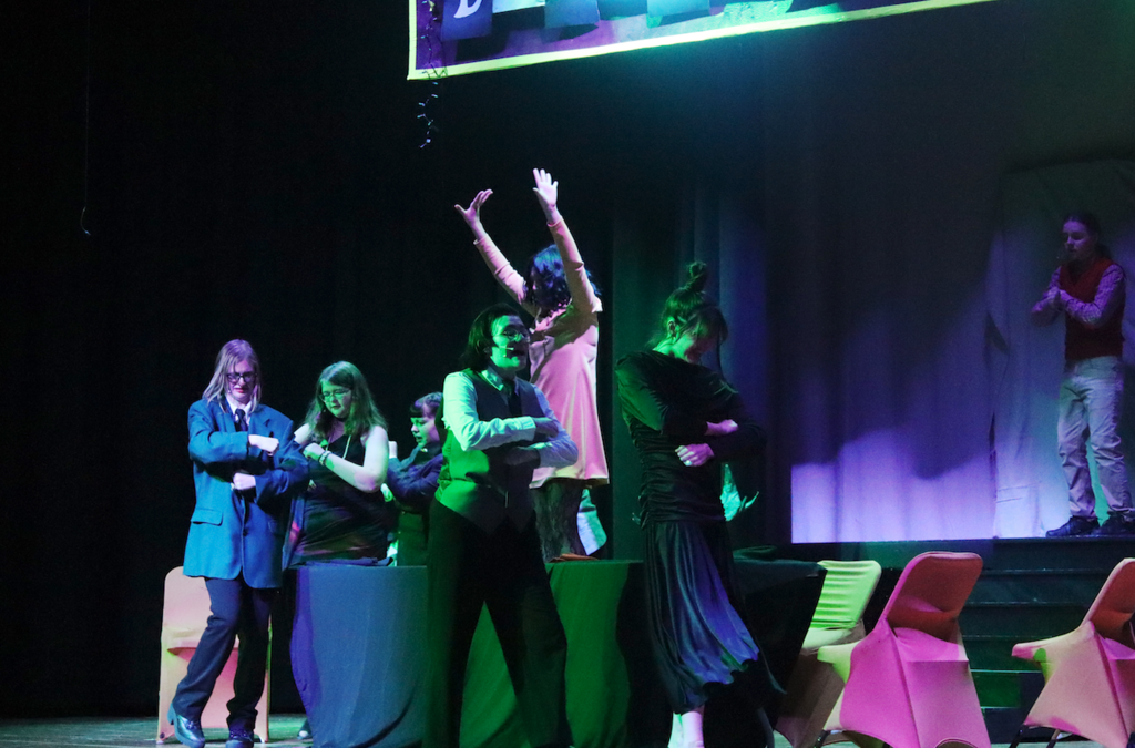 students dancing around table on stage