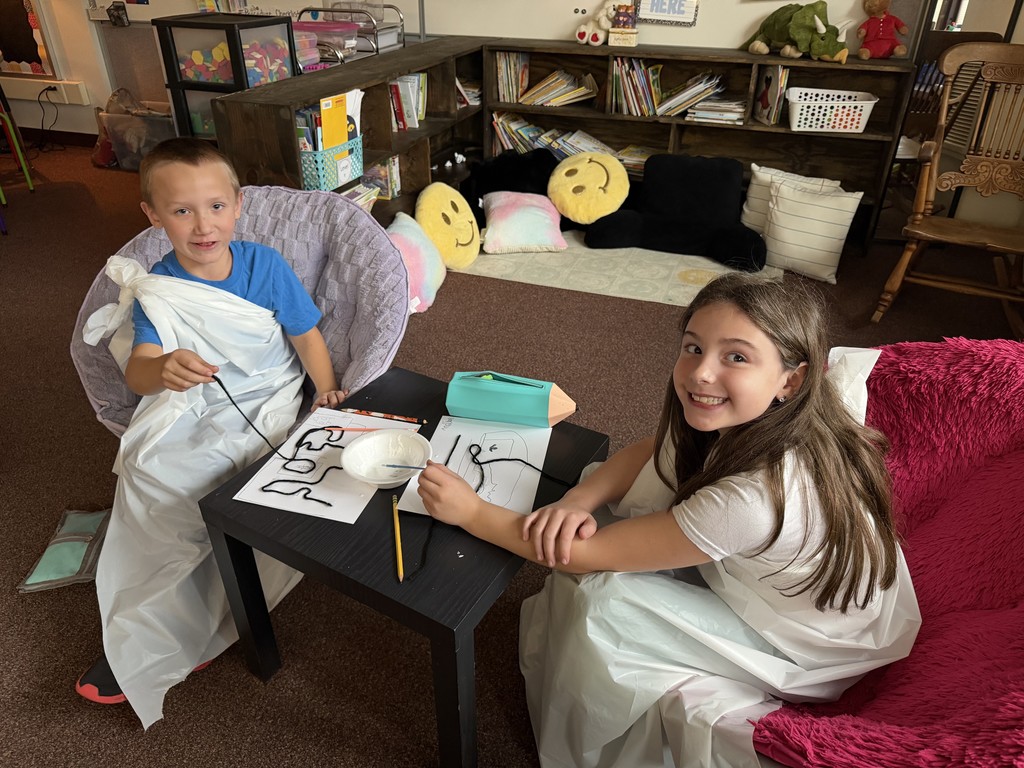 two kids dressed in togas drawing