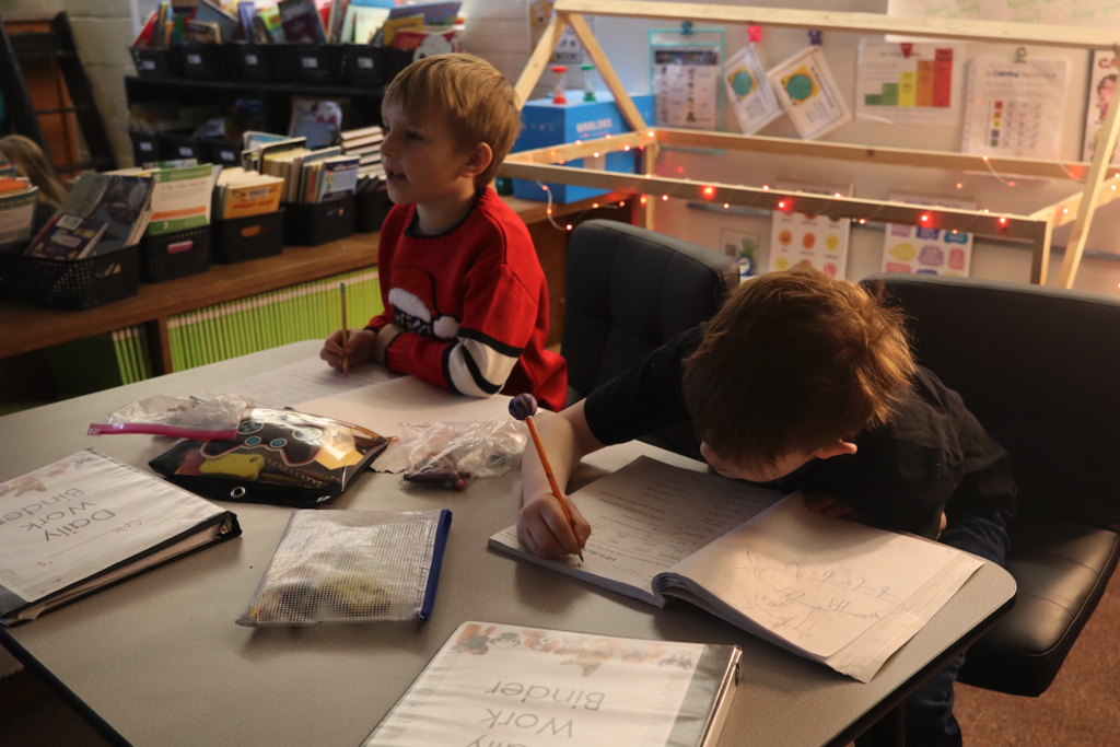 little boys writing in workbooks at desk