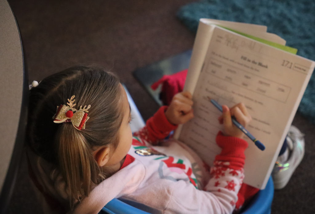 little girl writing in workbook
