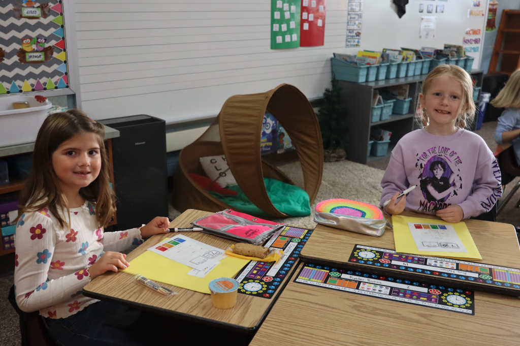two students writing at their desk with breakfast