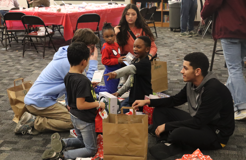 little boy opening presents with older kids