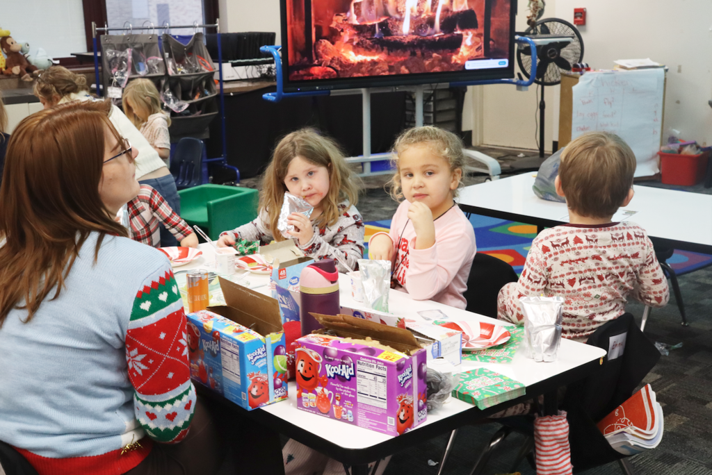 two little girls sitting at a table drinking juice boxes