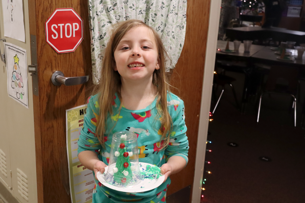 little girls showing off Christmas tree she made