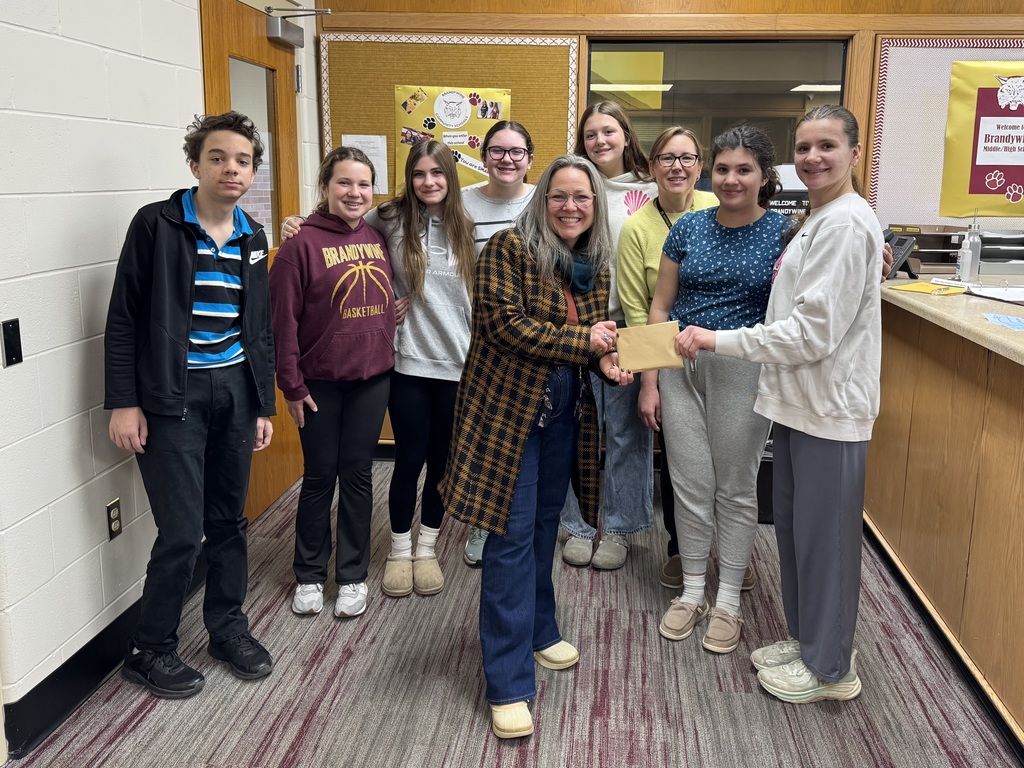 students with woman accepting a check donation