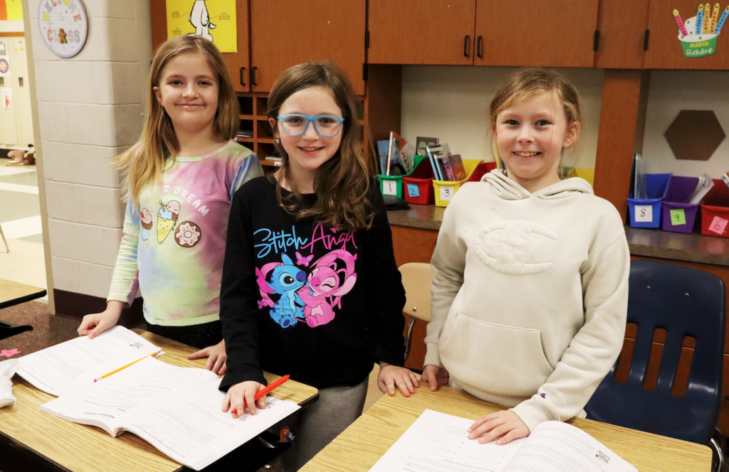 three girls smiling working on math work