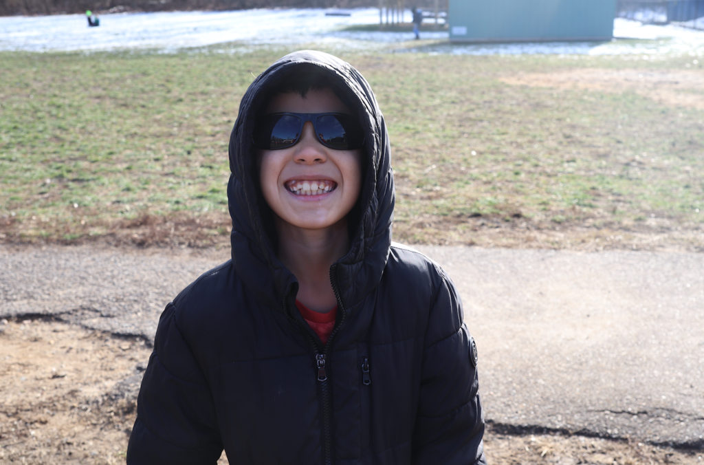 little boy smiling in coat in sunglasses