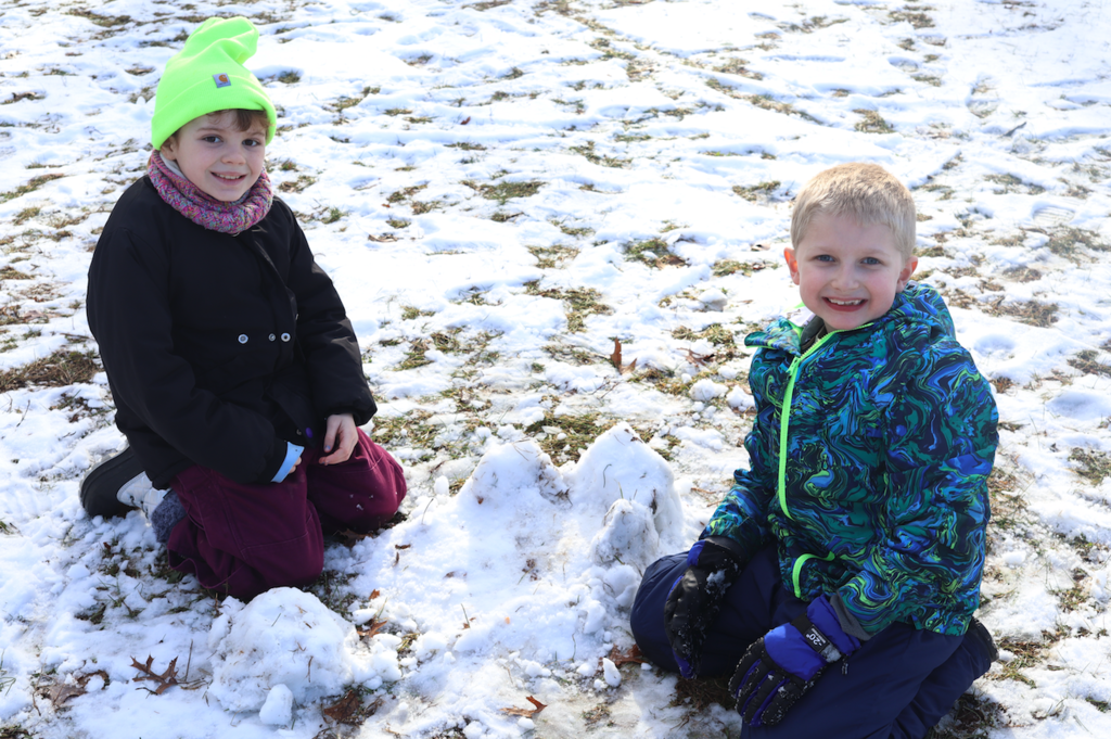 a little girl and a little boy playing in the snow