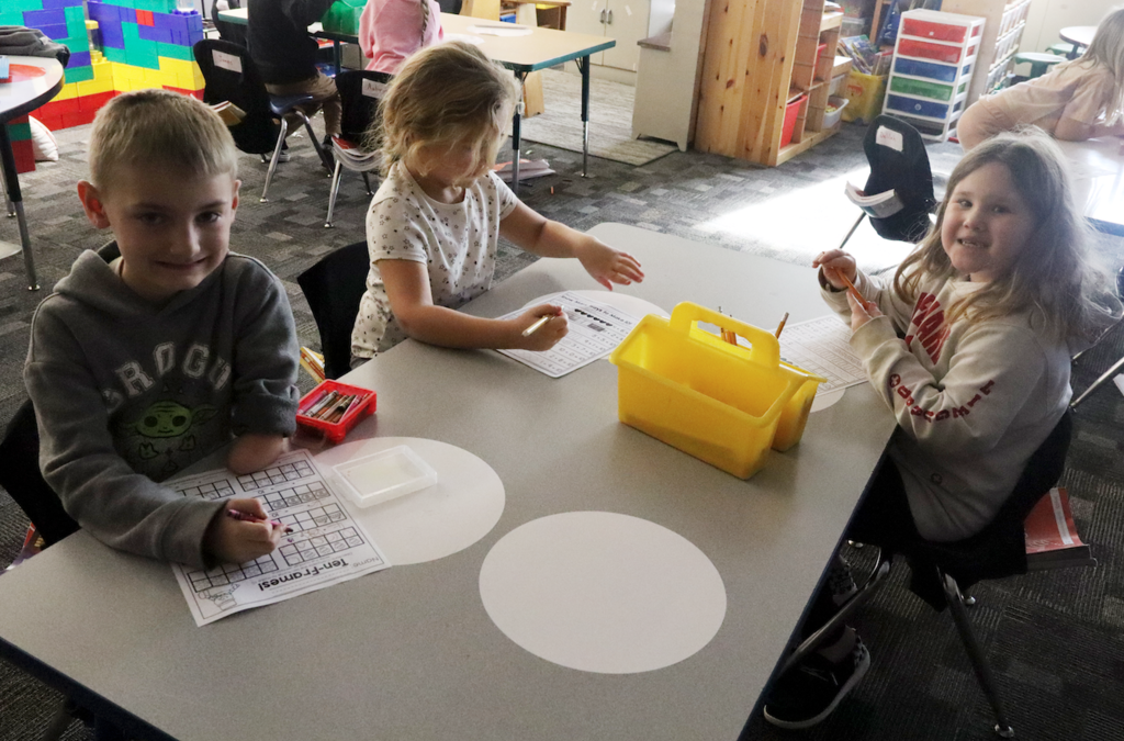 two little girls and a little boy working on a worksheet