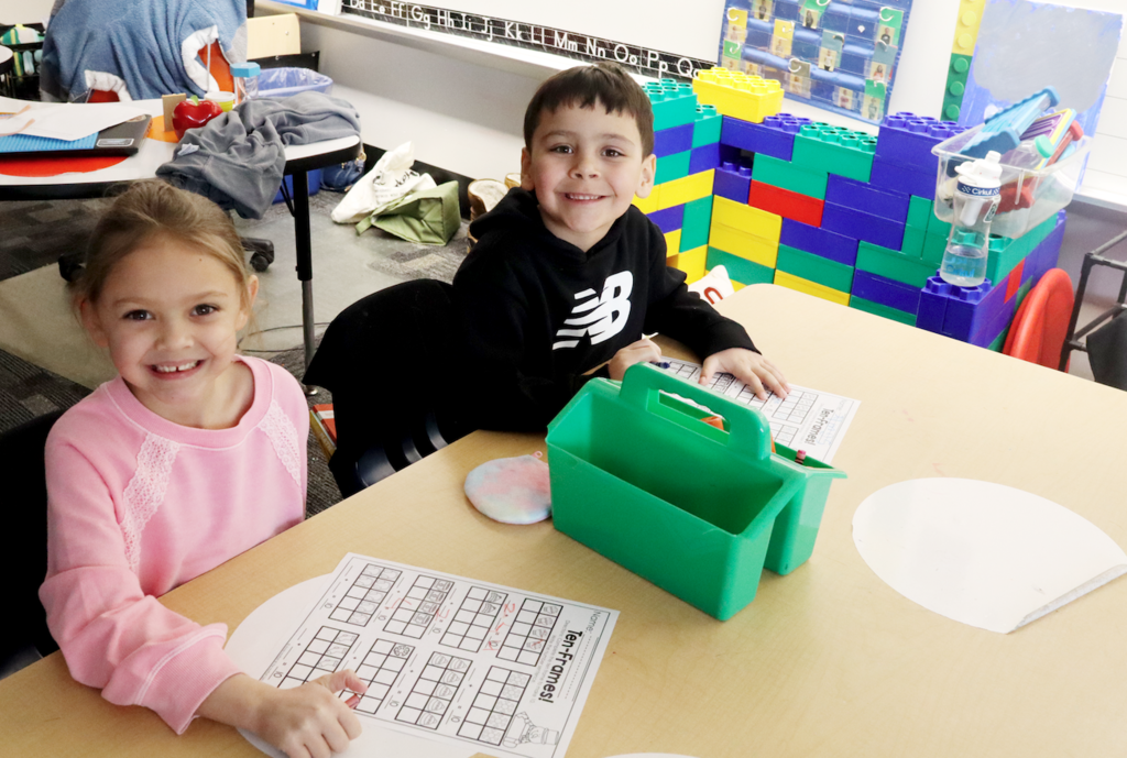 a little boy and a little girl working on a worksheet