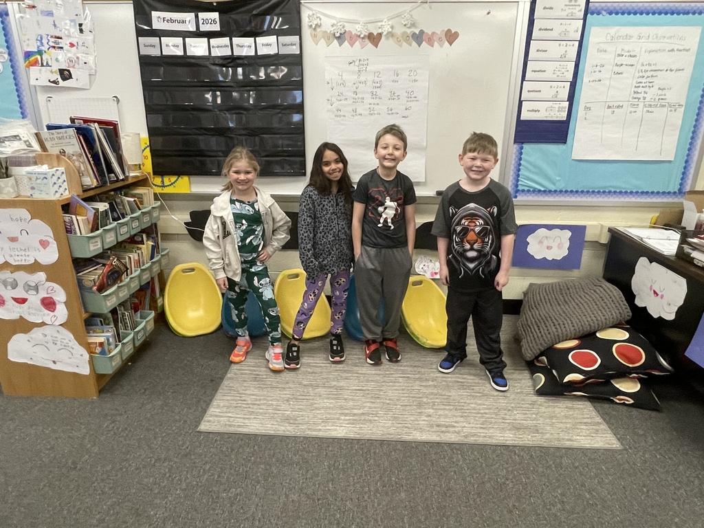 four students standing in their classrooms