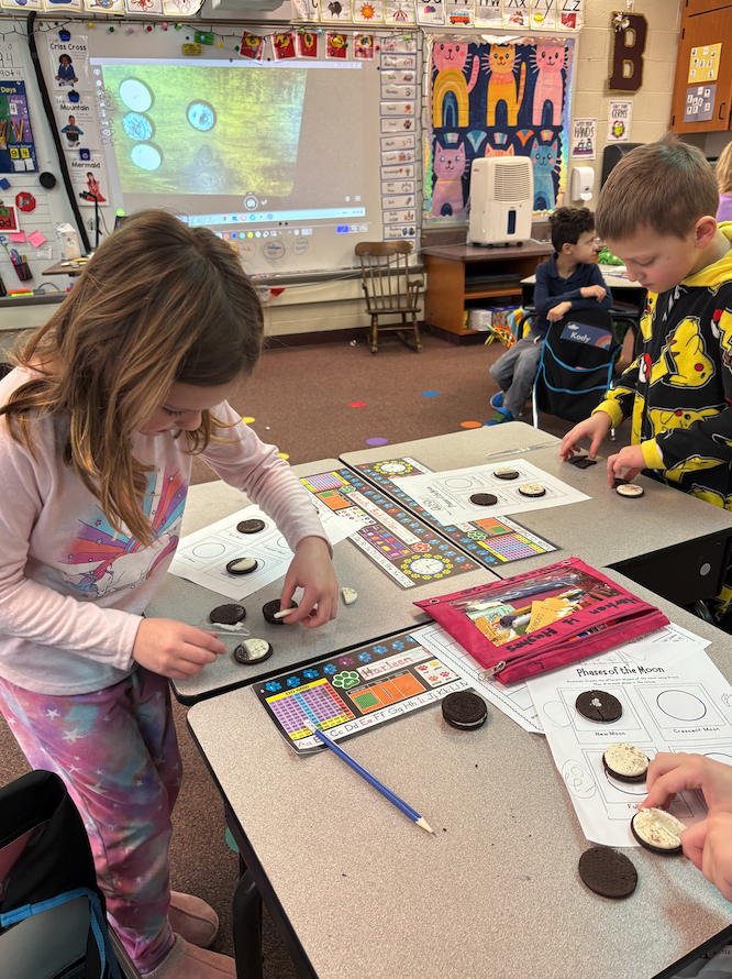 little girl and boy creating moon phases out of Oreos