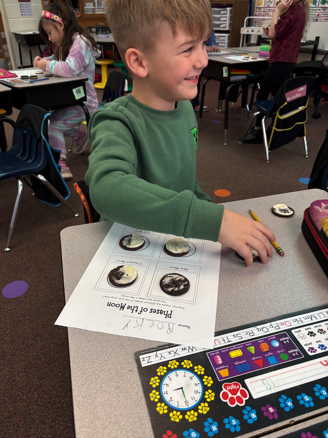 little boy smiling making moon phases out of Oreos