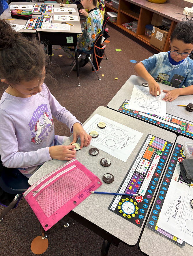 little girl and boy creating moon phases out of Oreos
