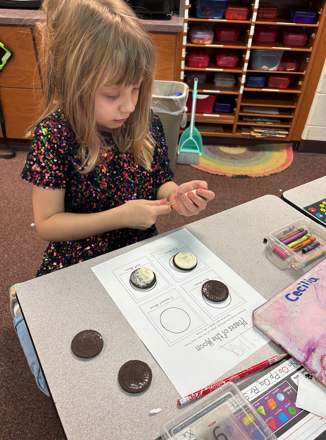 little girl creating moon phases out of Oreos