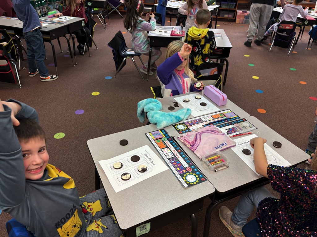 students at table with Oreo moons raising their hands