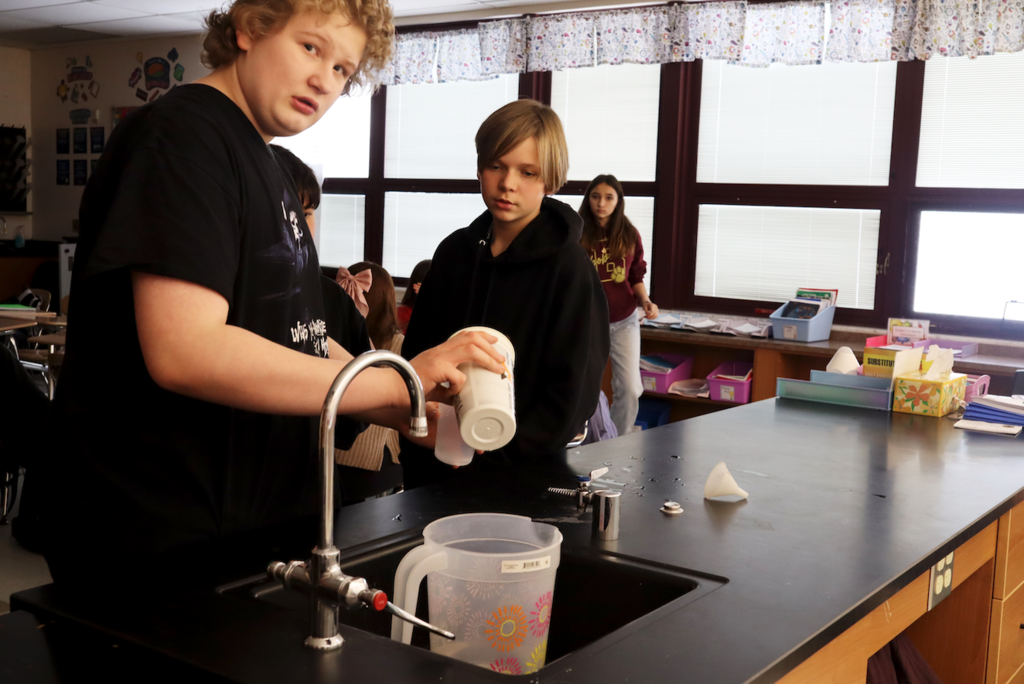 student pouring cabbage juice into cup