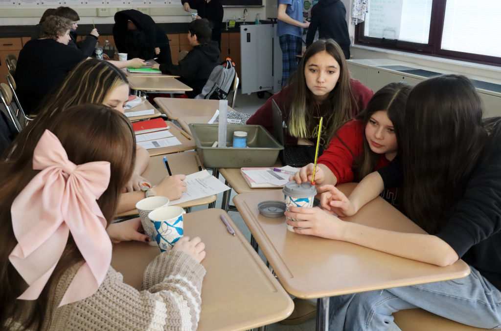 students putting thermometer in a cup
