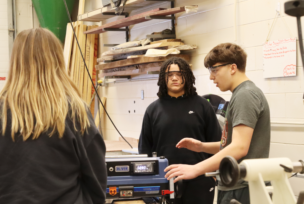 two students showing how the wood machine works
