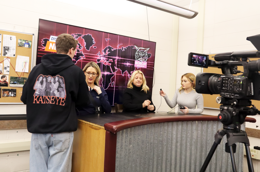 students hooking up adult anchors to microphones