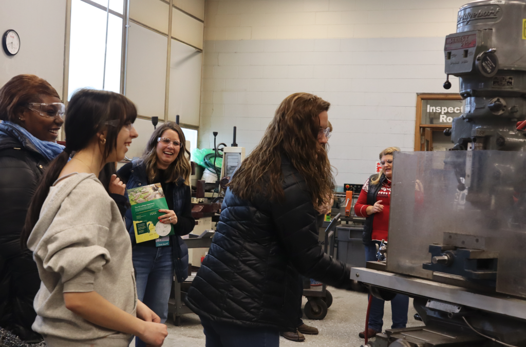 counselor running machine in machine shop with student standing by them