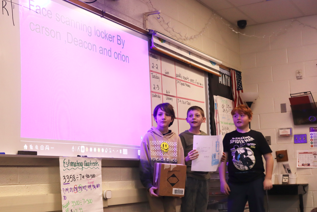 three boys presenting at front of the class