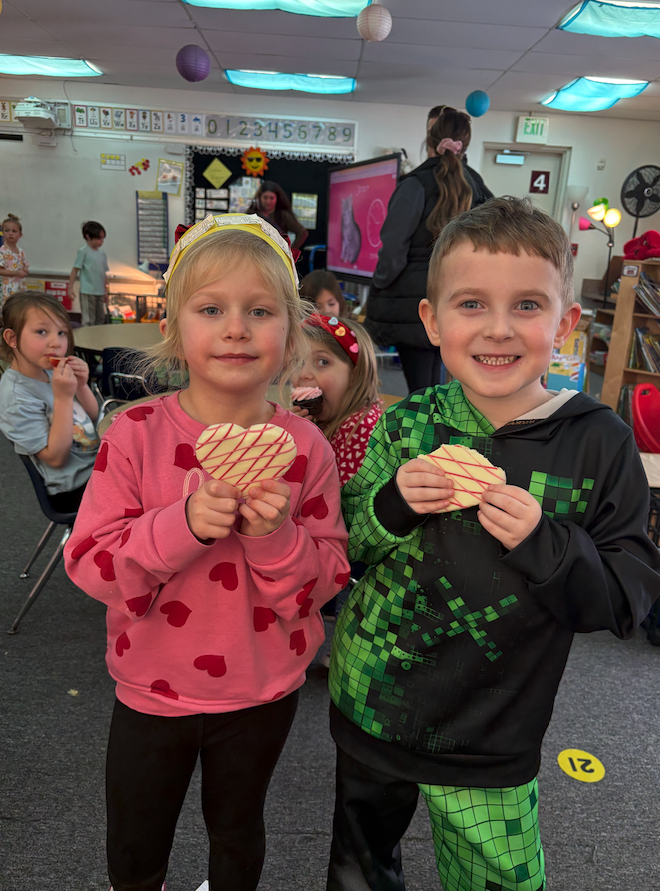 two kids holding heart shaped cookies