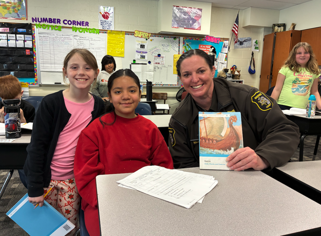 two girls with deputy mcG with a book