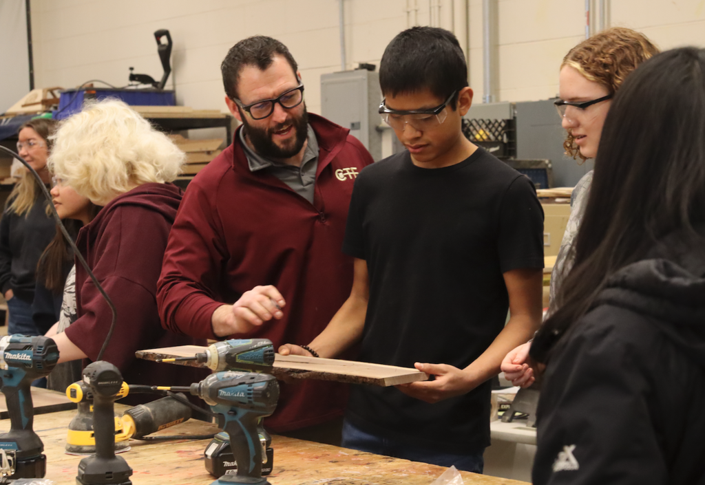 teacher helping student in woodshop