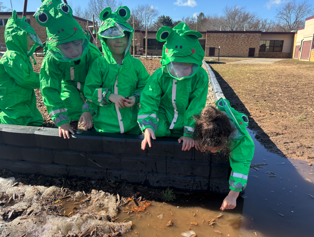 little kids in froggy outfits looking at water