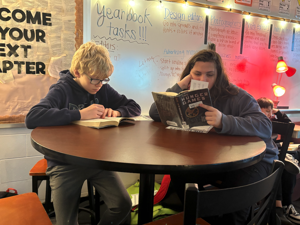 two boys reading books at table