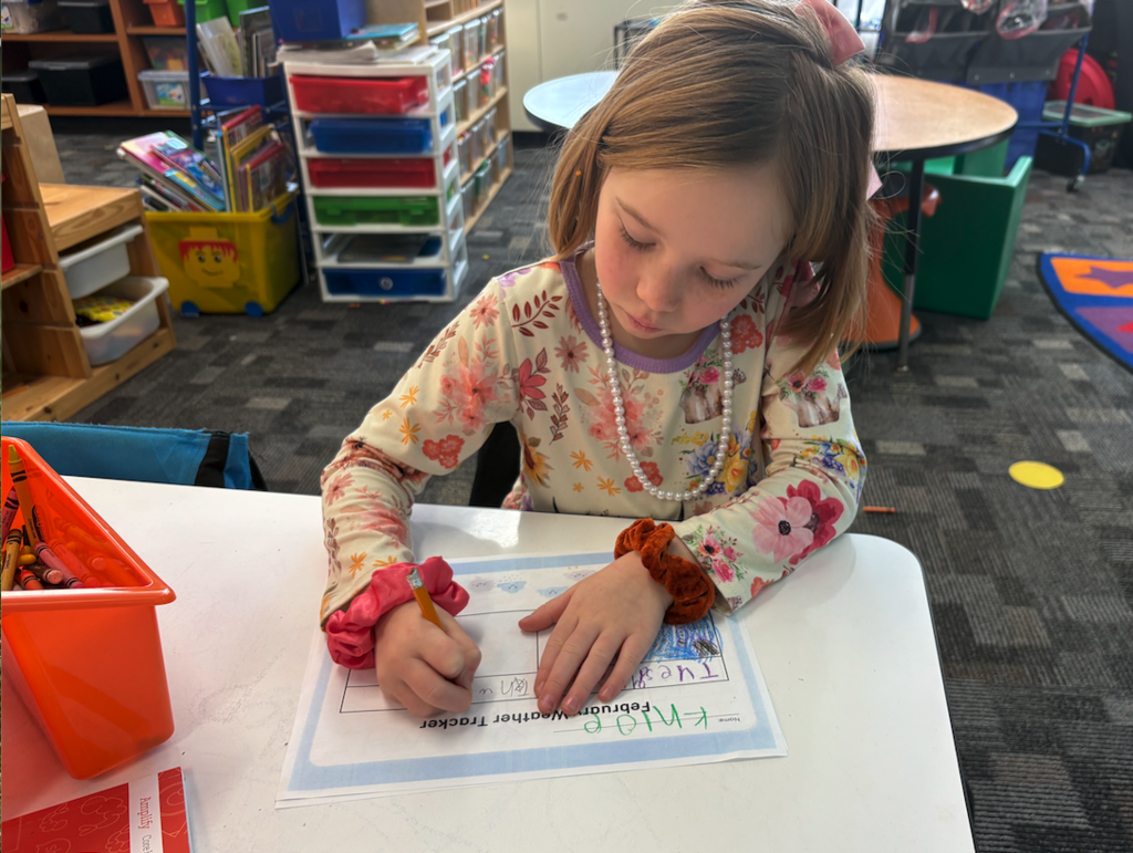 little girl working on writing out the weather for the week