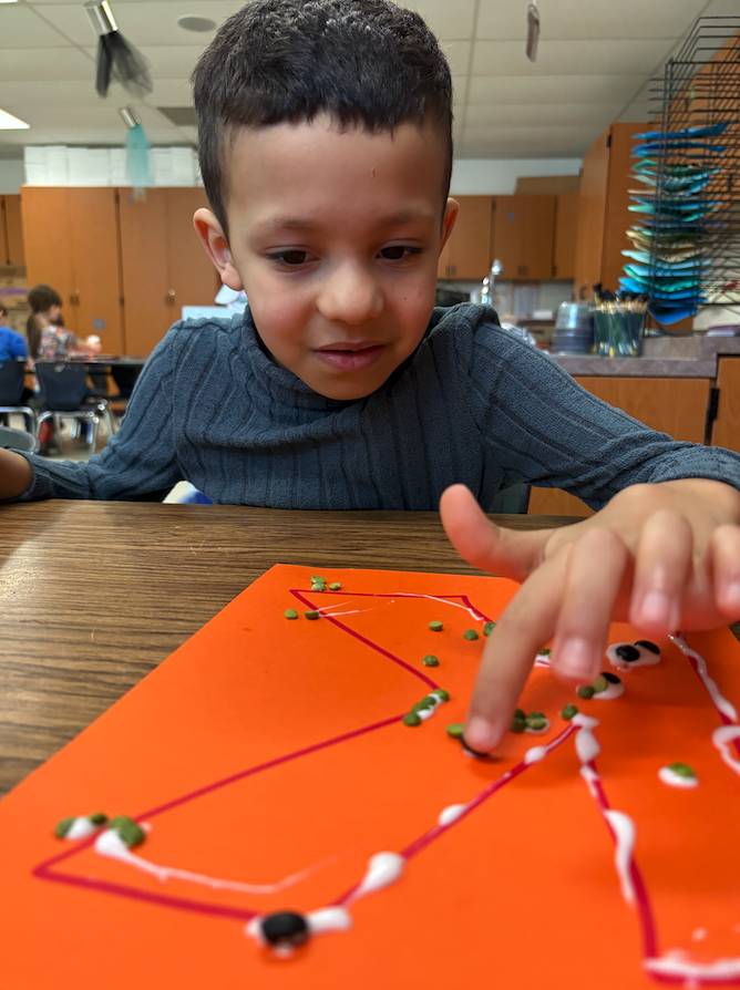 young boy creating bean art
