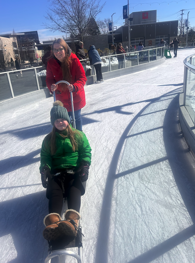 two girls pushing around ice rink