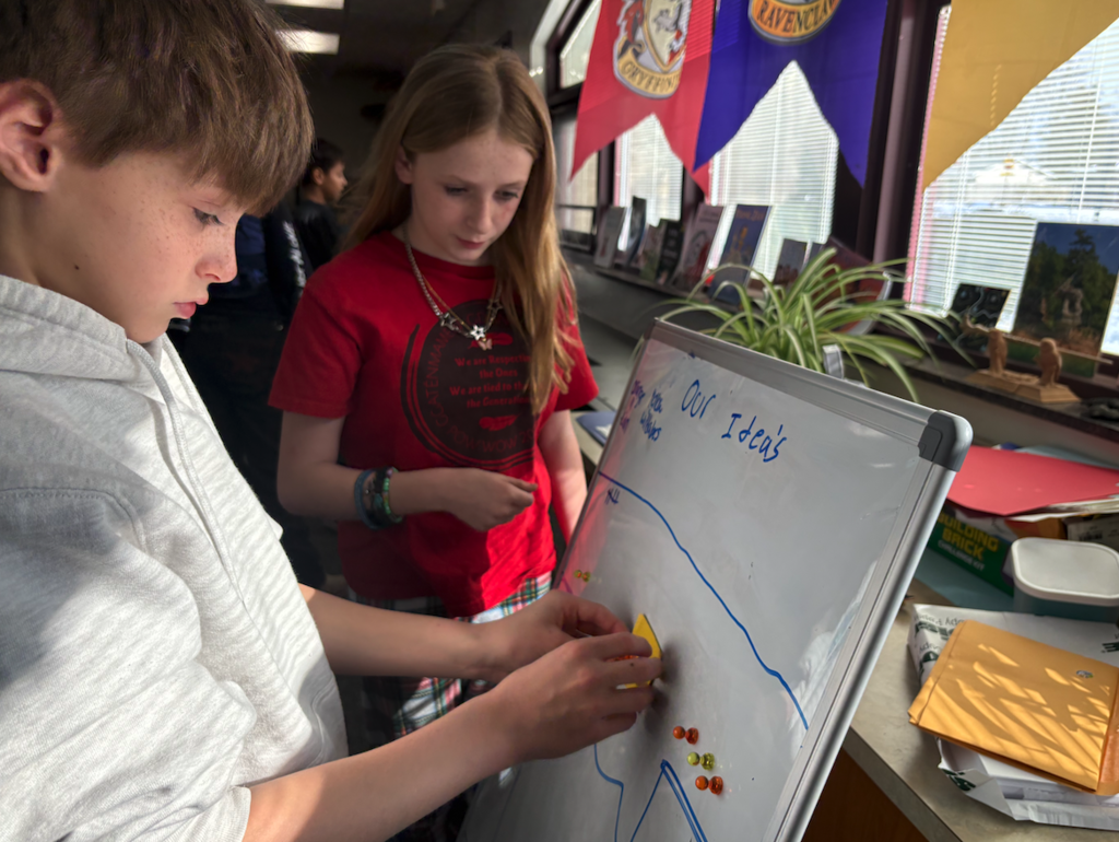 group of two kids working on white boards