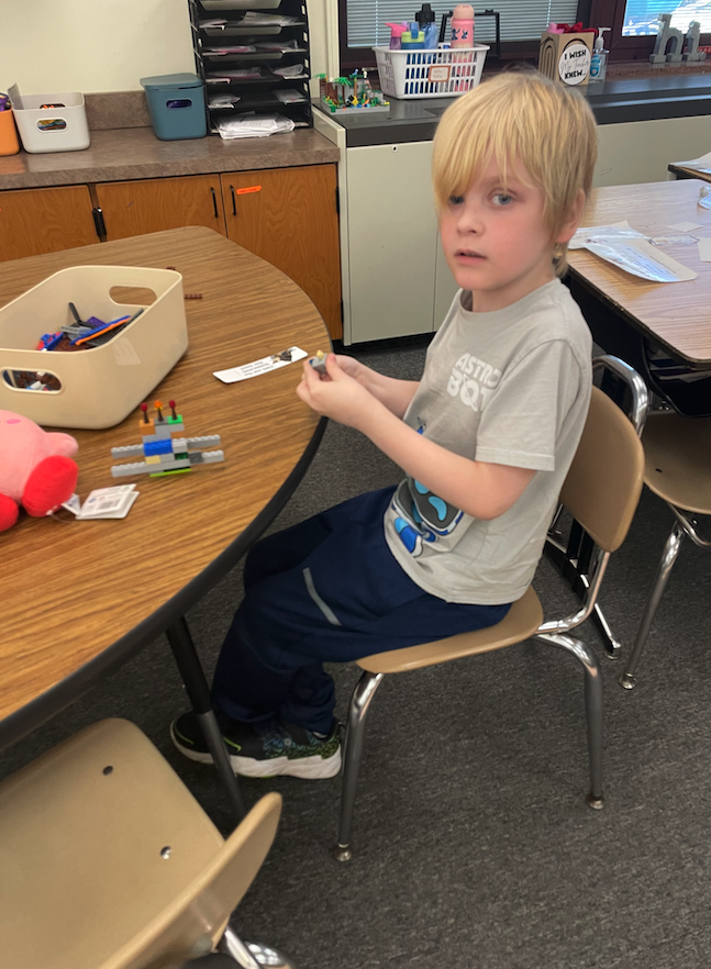 little boy playing with legos at table