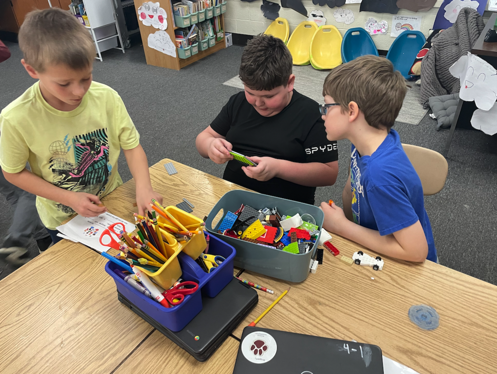 three boys playing with legos at table