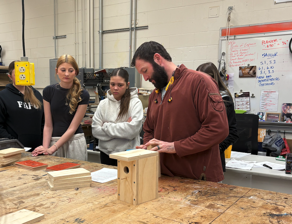 teacher showing how to build a birdhouse