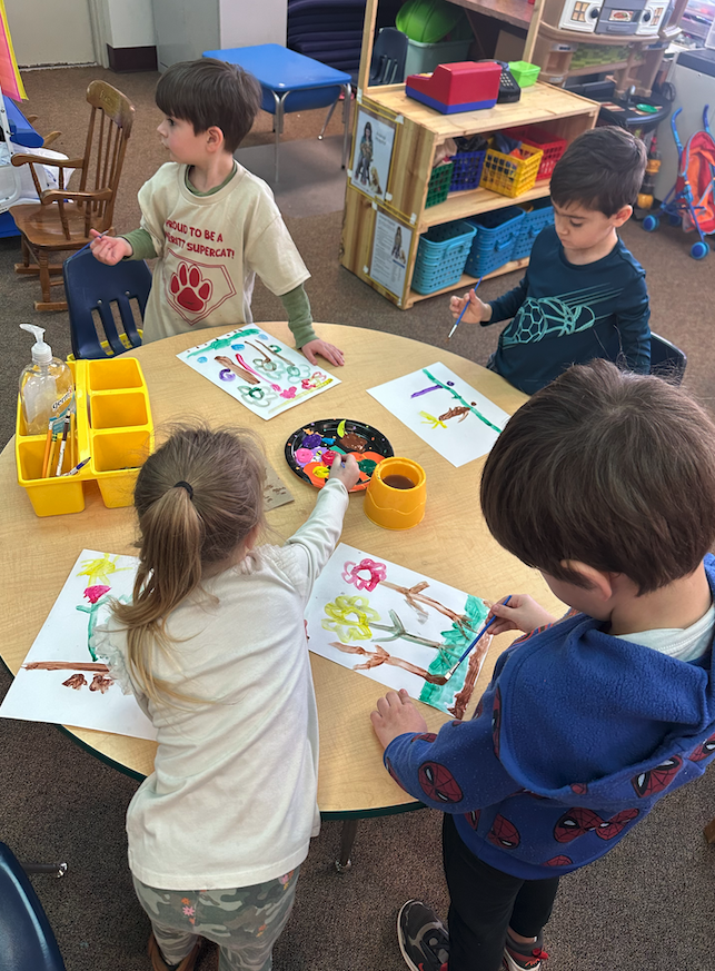 students sitting around tables painting flowers