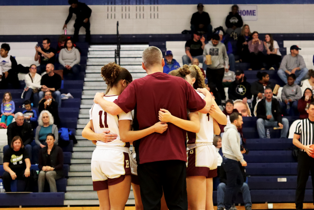 coach huddled with basketball players 