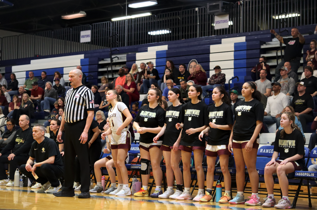 asketball players on bench standing up watching game