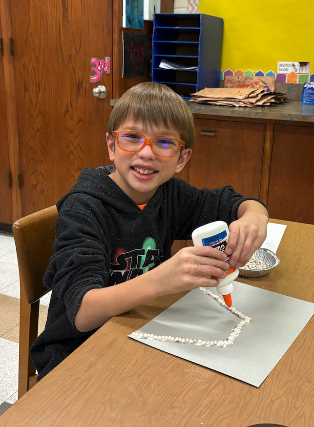 little boy working on be a art with glue
