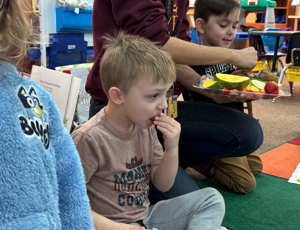 little boy trying fruit and veggie