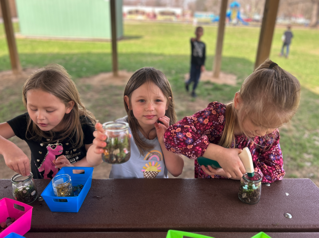 three little girls at table making terrariums