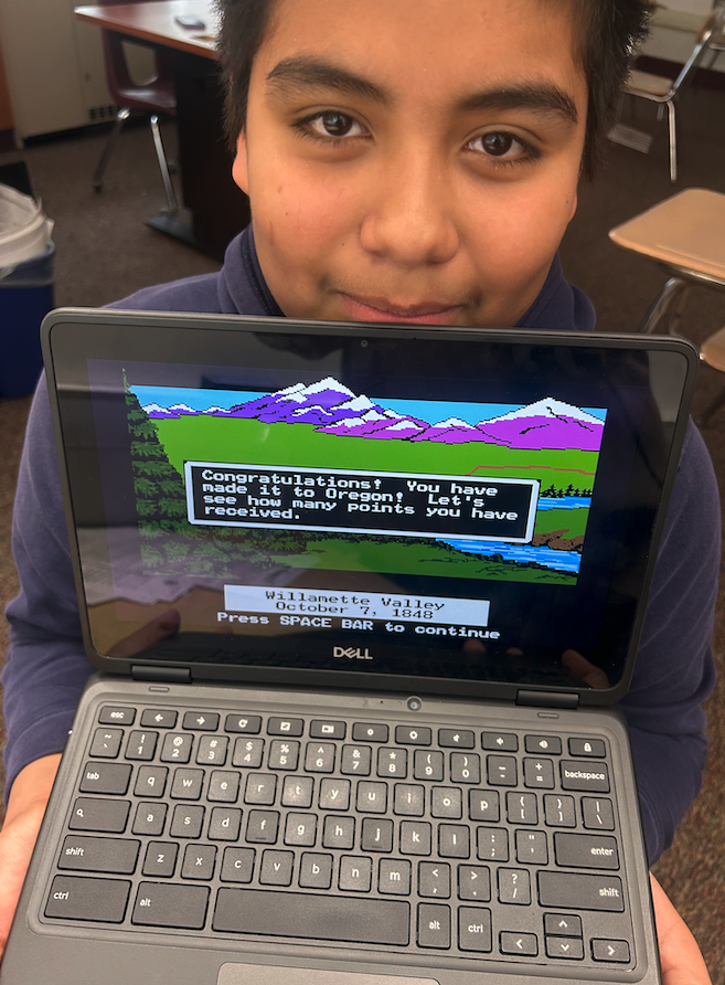 kid holding computer with Oregon trail
