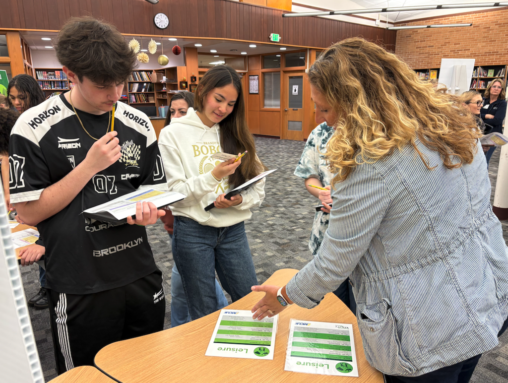 two students standing at table budgeting for leisure items