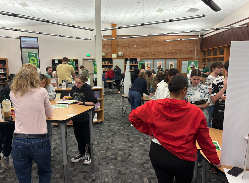 students in library standing around at various tables