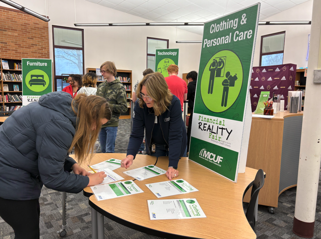 young woman standing at table with bank employee budgeting clothing and personal care