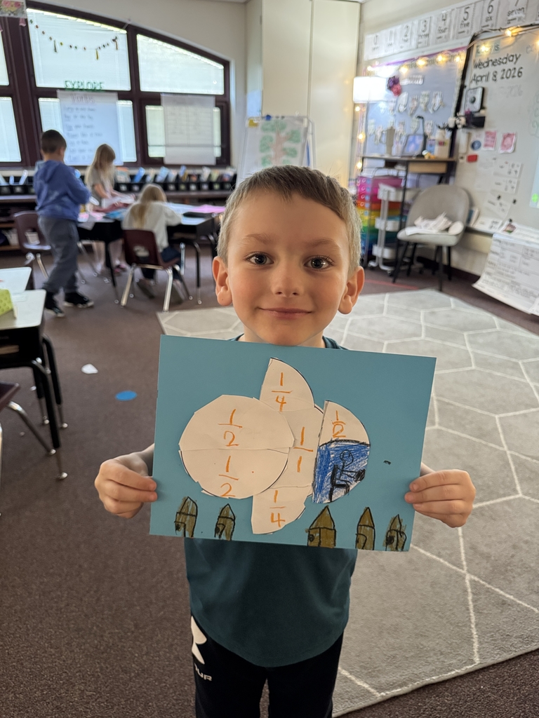 young boy holding up picture he made in classroom